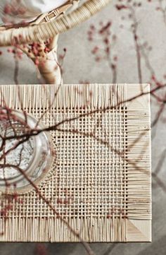 the table is made out of bamboo and has a glass vase on it