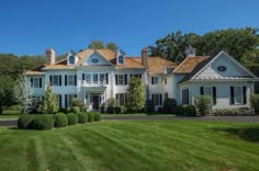 a large white house sitting on top of a lush green field