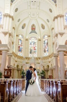 a bride and groom standing in front of the alter at their wedding ceremony with stained glass windows