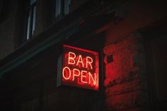 a neon sign that reads bar open on the side of a building