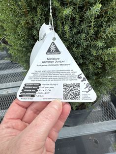 someone is holding up a tag in front of a plant that has been clipped to it