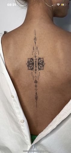 the back of a woman's neck with an intricate tattoo design on her lower back