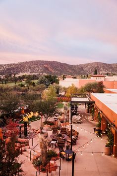 an outdoor seating area with tables and chairs in the middle of it, surrounded by mountains