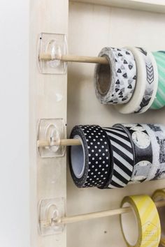 several rolls of washi tape are hanging on the wall with wooden pegs to hold them