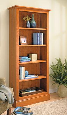 a wooden book shelf with books on it in a living room next to a couch