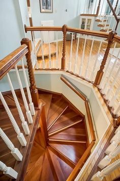 a spiral staircase with wooden handrails and white railing on the top floor in a home