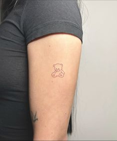 a woman with a small tattoo on her arm that is shaped like a teddy bear