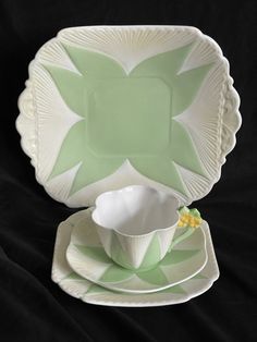 a green and white dinnerware set on a black cloth with a flower design in the center