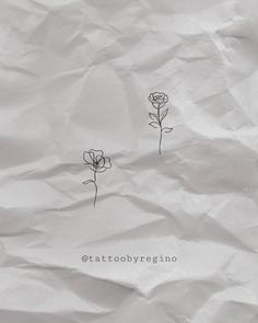 two small flowers are sitting on top of some white paper with the words tattoo by regino