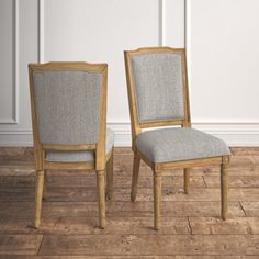 two chairs sitting next to each other on top of a hard wood floor in front of a white wall