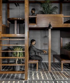 a person sitting on a bench in front of a bunk bed with stairs and plants