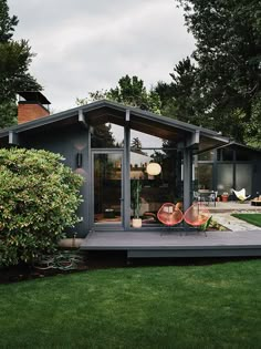 a small house sitting in the middle of a lush green yard with trees and bushes