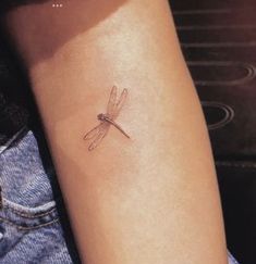 a small dragonfly tattoo on the arm