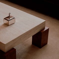 a wooden table with a small silver object on it's end sitting on the floor