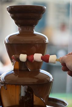 a chocolate fountain with marshmallows and strawberries on it