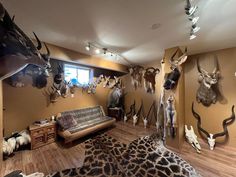 a living room filled with lots of deer heads on the wall and animal fur rugs