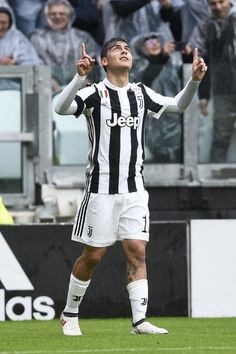 a man standing on top of a soccer field holding his hands up in the air