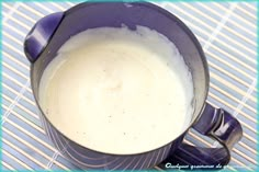 a blue mug filled with milk sitting on top of a table