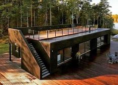 a house that is sitting on top of a wooden deck next to water and trees