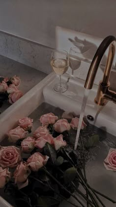 roses are being washed in a sink with water running from the faucet and wine glasses