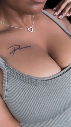 a woman with a heart tattoo on her chest and arm, wearing a gray top