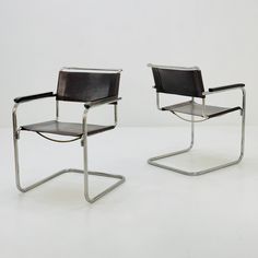 two black leather chairs sitting next to each other on top of a white flooring