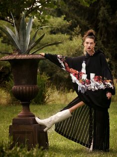 a woman is posing in front of a plant