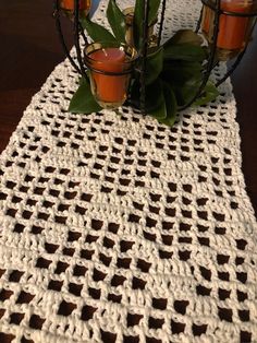 a crocheted table runner with candles on it