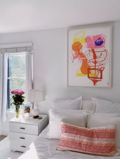 a bedroom with white bedding and pink flowers in vases on the side table