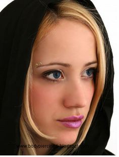 a woman with blonde hair and blue eyes wearing a black hoodie looking at the camera