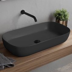 a bathroom sink sitting on top of a wooden counter next to a potted plant