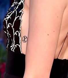 the back of a woman's dress with tattoos on her left arm and shoulder