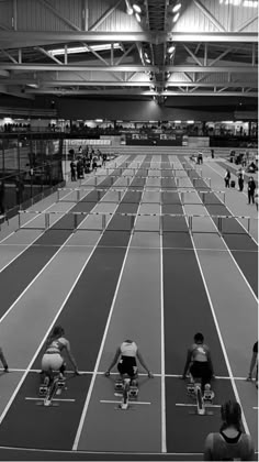 black and white photograph of people riding bikes on a track