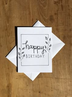 a card with the words happy birthday written on it in black and white, sitting on top of a wooden table