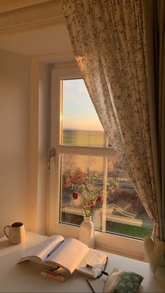 an open book sitting on top of a table next to a window with a view