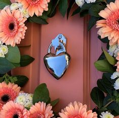 a heart shaped mirror sitting on top of a door surrounded by flowers