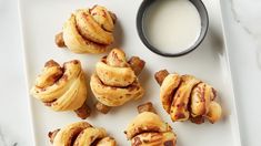 some cinnamon rolls on a white plate next to a cup of milk