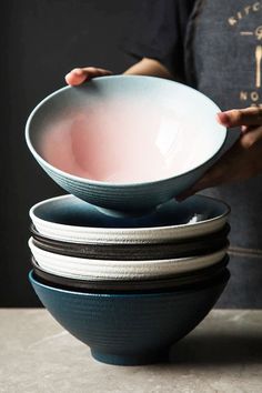 a person holding a stack of bowls on top of each other