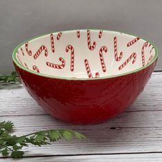 a red and white bowl with candy canes printed on the side sitting on a wooden table