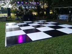 a large checkered dance floor in the middle of a lawn with lights on it