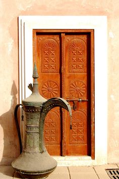 a large metal vase sitting in front of a wooden door