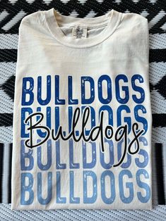 Get this popular new Bulldogs stacked text shirt and show off your school spirit in style!  Each shirt is printed in-house by me using high-quality materials on a Comfort Colors shirt, known for its exceptional comfort, style, and durability. Available in unisex sizes S to 3X, and youth sizes, we've got you covered regardless of your preferred fit. The Bulldogs stacked text Shirt features a classic crew neck and short sleeves, making it suitable for year-round wear. The flattering silhouette ensures a comfortable and stylish fit for both men and women. Please note that ivory is ONLY available in Adult sizes!  Note: As each shirt is individually printed, slight variations in color and placement may occur, adding to the uniqueness and charm of your Preppy Bulldogs Shirt. Your shirt will come Long Sleeve Cheer Shirts, Bulldog Volleyball Shirts, Middle School Spirit Wear, School Mascot Shirt Designs, Wildcats Spirit Shirts, School Spiritwear Ideas, Sublimation School Spirit Shirts, Cricut School Spirit Ideas, Cheerleading Shirts Designs Spirit Wear