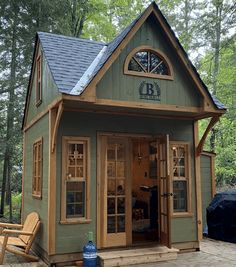 a small green building with a porch and windows