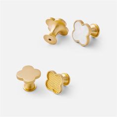 three pairs of gold and white studs with flowers on them, one has a flower in the middle