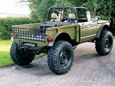 a green truck parked on top of a brick road