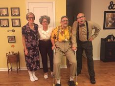 three older people are posing for a photo in front of a yellow room with pictures on the wall