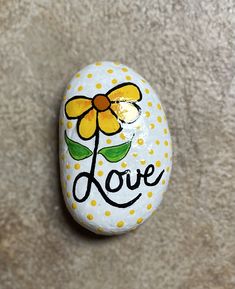 a painted rock with the word love written on it and a flower in the center