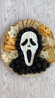 a plate with crackers and blackberries in the shape of a face