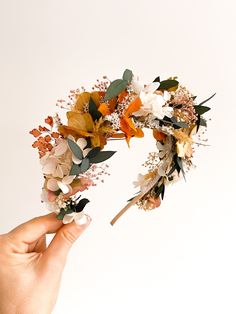 a hand is holding a flower crown with flowers on it