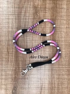 a pink and white beaded lanyard on a wooden surface with the name alex dizen